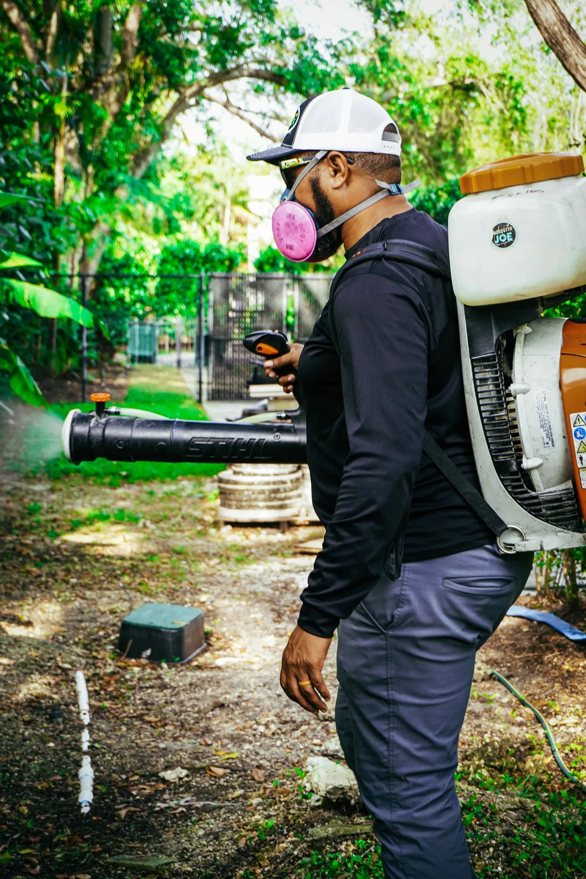 A technician using a mist blower in a garden